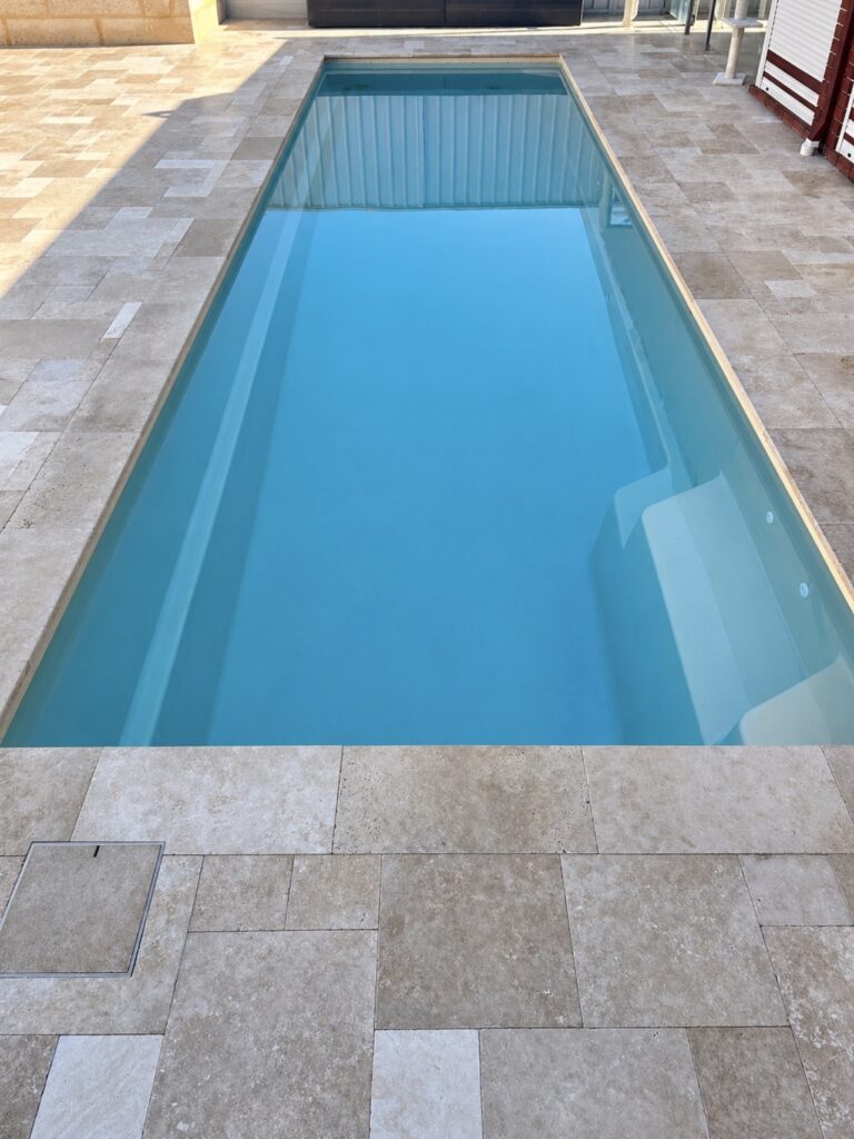 Travertine pool area paving with custom flush access lid to a backyard in Woodvale. 