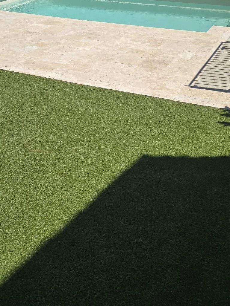 Travertine paving and artificial lawn installation for pool area.